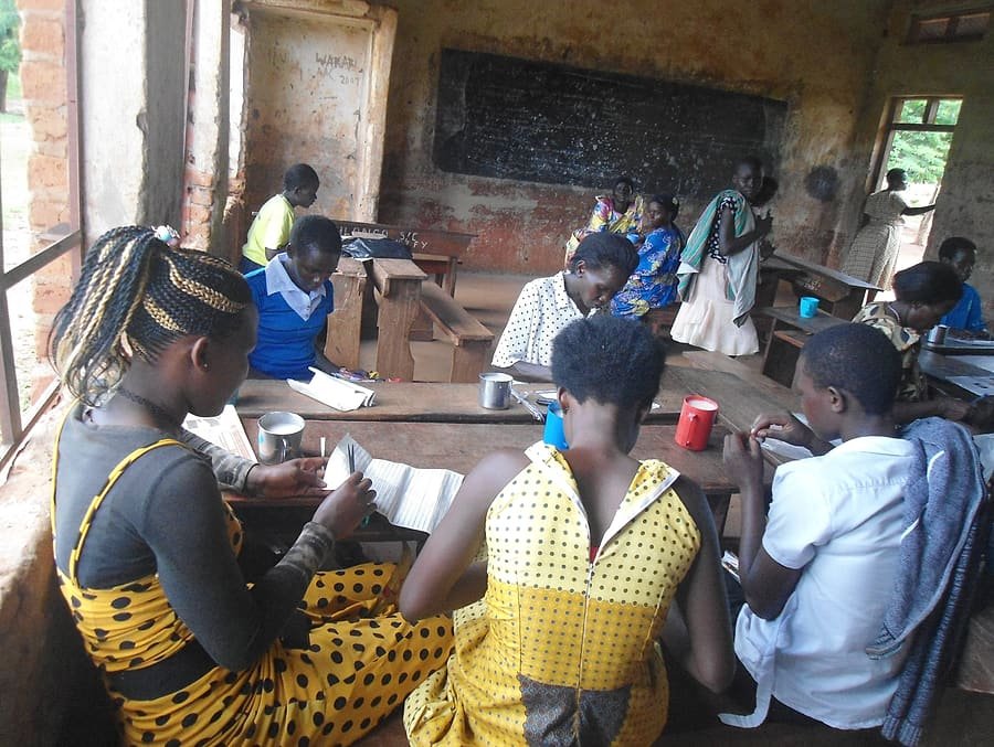 Young people seated with notebooks during a Kiyunga Social Service Centre training session in a community classroom.